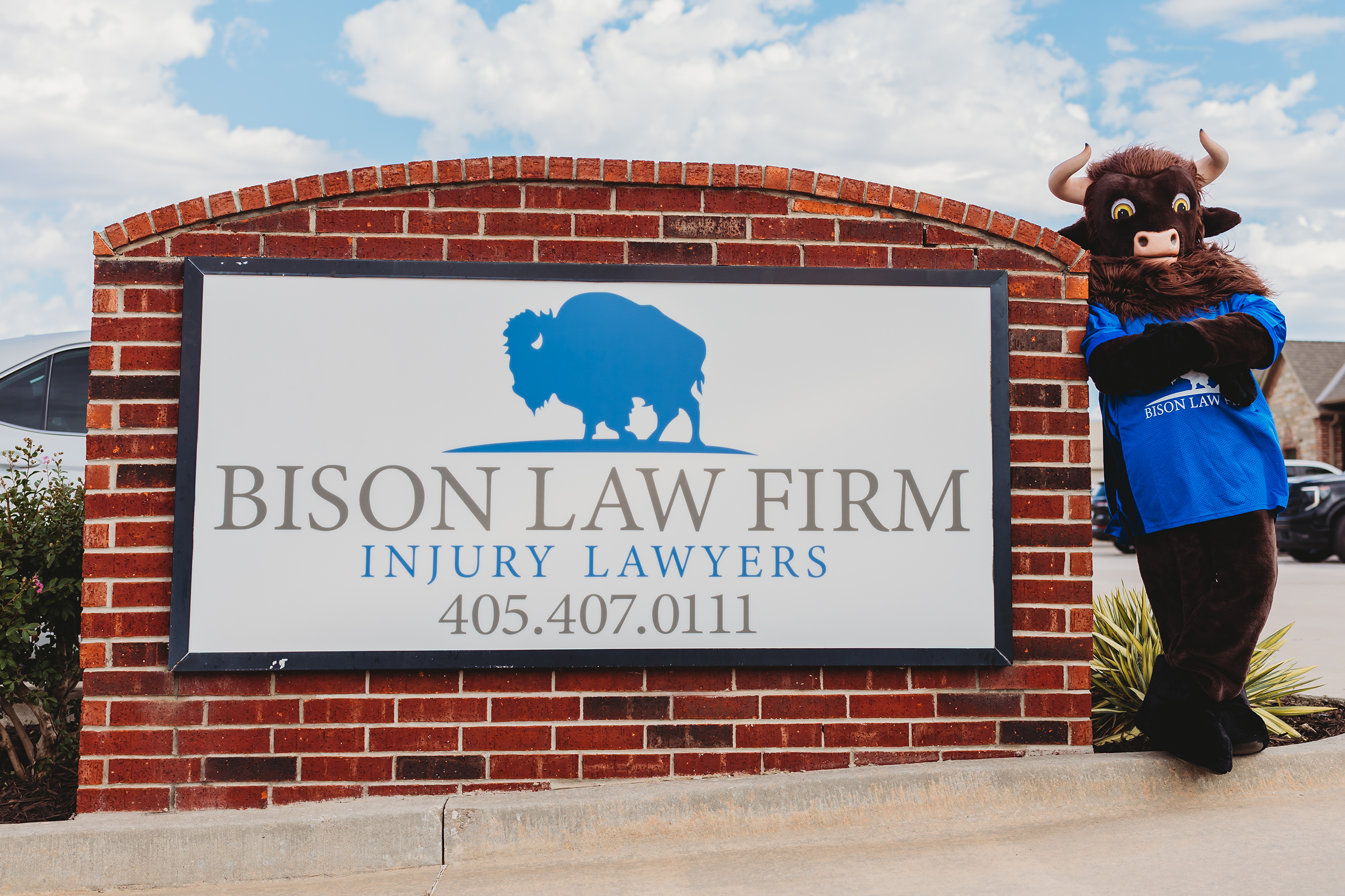 Tiffany the Bison mascot standing next to the Bison Law Firm sign